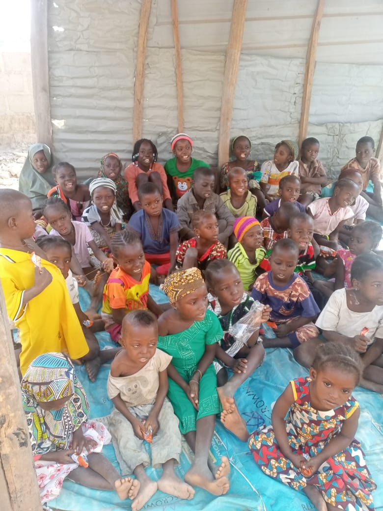 Children seated on the floor smiling and learning from a teacher